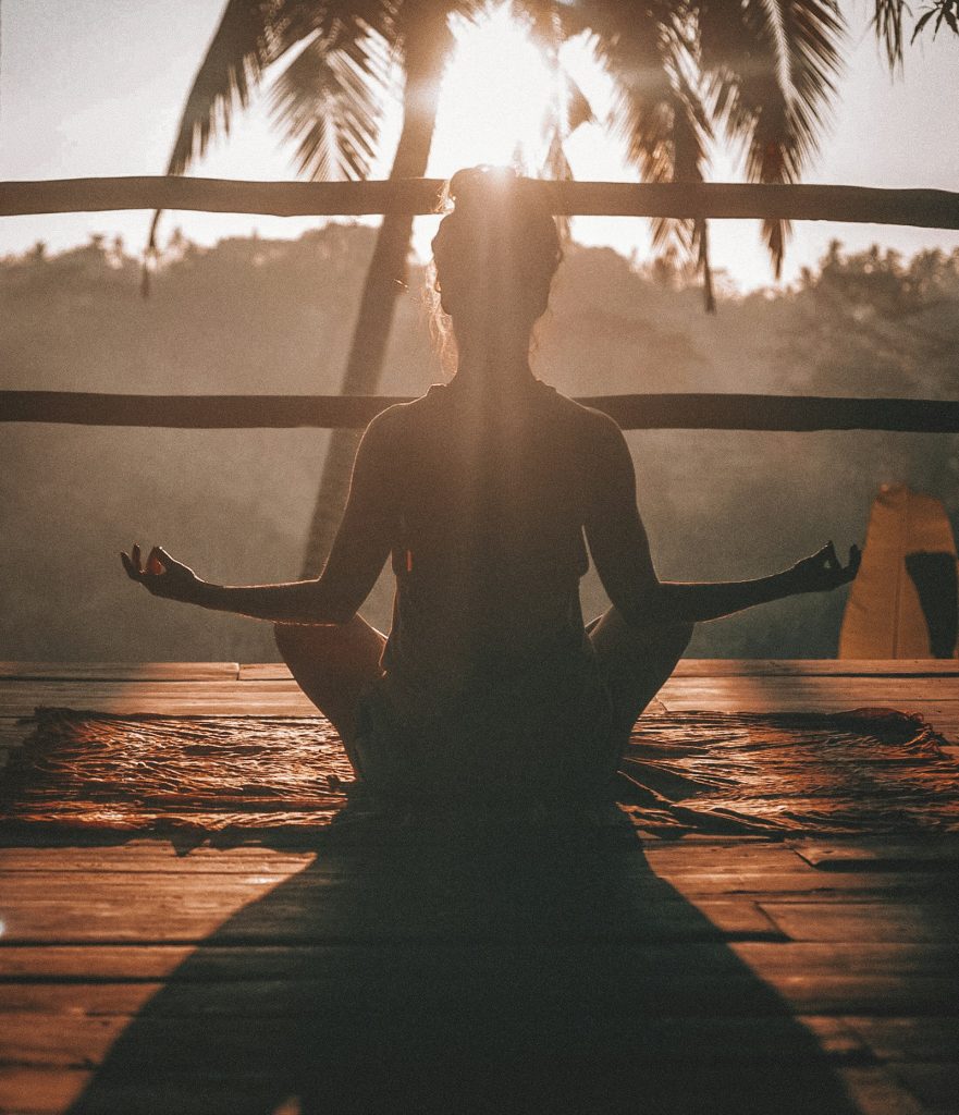 Silhouette of a woman meditating at sunset among palm trees